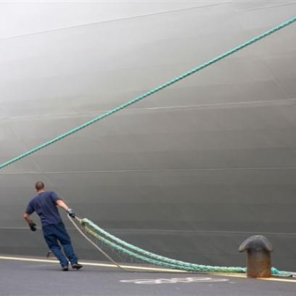 havenwerker legt schip aan kade en bolder aan