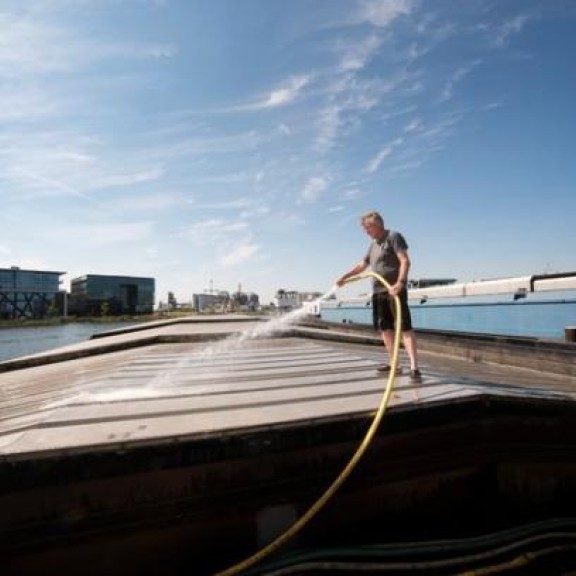 Binnenvaartschipper spuit dek schip schoon