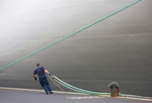 havenwerker legt schip aan kade en bolder aan